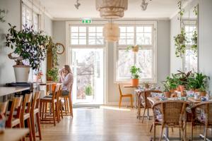 a woman sitting at a table in a restaurant with plants at Wij Trädgårdar in Ockelbo