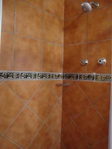 a shower with a glass door and brown tiles at Trafalgar Chalets Unit 1 in Southbroom