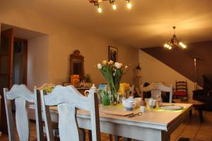 una mesa de comedor con un jarrón de flores. en Le relais du cheval blanc en Tenneville