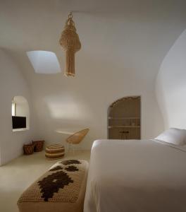 a bedroom with a bed and a chair and a television at Suite Home Santorini in Fira