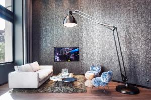 a living room with a white couch and blue chairs at Motel One Basel in Basel