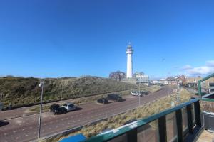 a view of a highway with a lighthouse in the background at Torenlicht - Zand I (36) in Egmond aan Zee +7 photos