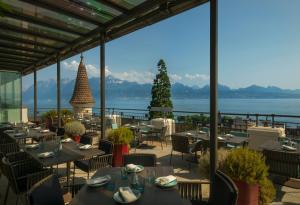 a restaurant with tables and chairs and a view of the water at Royal Savoy Hotel & Spa in Lausanne