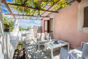 a patio with white chairs and tables and a pergola at Salina Case Vacanza in Malfa