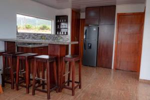 a kitchen with a bar with stools and a refrigerator at Chalet Familiar Full equipado! Jacuzzi privado 30 minutos gratis! in Sogamoso