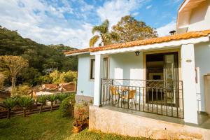 a white house with a balcony with chairs at Pousada Il Villaggio in Santo Antônio do Pinhal