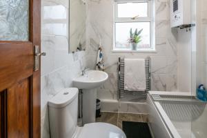 a bathroom with a toilet and a sink and a window at Blue Rose Cottage in Burry Port