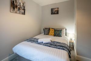 een kleine slaapkamer met een bed met kussens erop bij Blue Rose Cottage in Burry Port