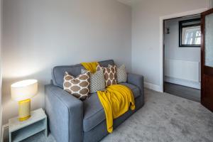 a living room with a gray couch with a yellow blanket at Blue Rose Cottage in Burry Port