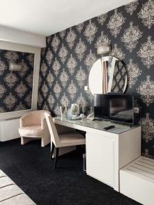 Habitación con escritorio, espejo y TV. en Hotel Concorde en Veliko Tŭrnovo
