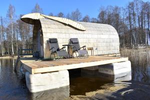 a house with chairs on a dock in the water at Usmas zaķīšu pirtiņa - Bunny house in Usma