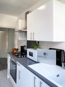 a kitchen with white cabinets and a box on the counter at The Baltic Townhouses by Serviced Living Liverpool in Liverpool