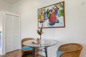 a glass table with two chairs and a painting on the wall at Turtle Cottage in Kailua