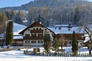 ein großes Gebäude im Schnee mit Bäumen in der Unterkunft Ferienwohnungen Kilianmühle in Berchtesgaden