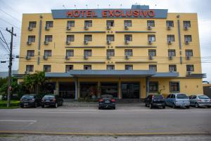 a yellow hotel with cars parked in front of it at Hotel Exclusivo in São José dos Pinhais