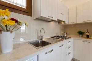 una cocina blanca con fregadero y un jarrón de flores en Villa Giuri, en Lido di Pomposa