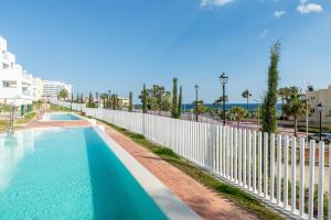 a swimming pool next to a white fence at VB Lar Bay - 3 BDR with Sea Views in Benalmádena