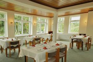a dining room with white tables and chairs and windows at Kenmare House in Kenmare