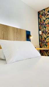 un grande letto bianco in una stanza con un muro di Kyriad Direct Chalon Sur Saone Nord a Champforgeuil Altre 33 foto