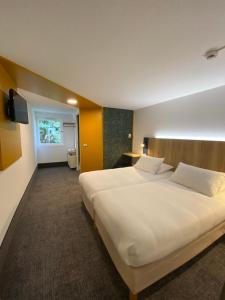 a large white bed in a hotel room at Kyriad Direct Chalon Sur Saone Nord in Champforgeuil