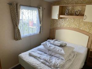 a bedroom with a bed with white sheets and a window at 3 bedroom 8 berth standard caravans with Hot Tub,Mountain Bikes in Tattershall