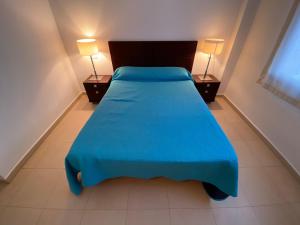 a blue bed in a room with two lamps at Apartamentos Entreplayas Altamar in Alcossebre