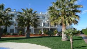 a white building with palm trees in front of it at Apartamentos Entreplayas Altamar in Alcossebre