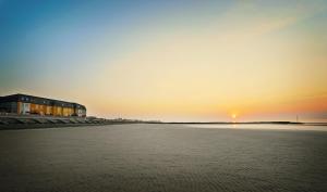 a beach with a building and the sunset in the background at The Beaches Hotel in Prestatyn