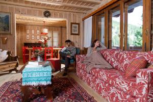 two women sitting on a couch in a living room at QC House - Chalet con Sauna in Santa Caterina Valfurva
