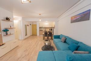 sala de estar con sofá azul y cocina en Moonlight Bliss Apartment en Mamaia
