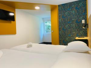 a room with two beds and a wall with a window at Kyriad Direct Chalon Sur Saone Nord in Champforgeuil