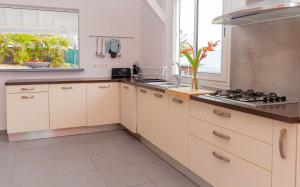 a kitchen with white cabinets and a stove top oven at Villa Arc-en-ciel in Le Moule