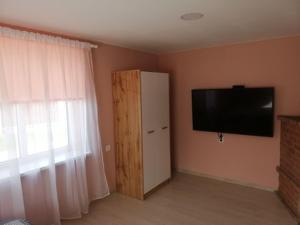 a room with a television and a door with a window at VĖJO16 in Biržai