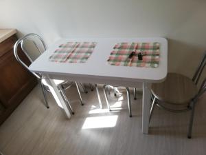 une table blanche avec deux chaises et une table avec dans l'établissement VĖJO16, à Biržai