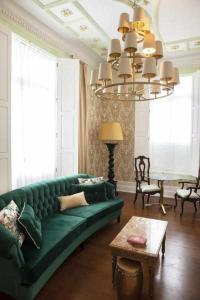 a living room with a green couch and a chandelier at Casa da Granja Boutique in Vila Nova de Gaia