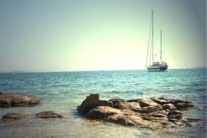 a boat in the ocean with rocks in the water at Appartamento Portisco sul Mare in Olbia
