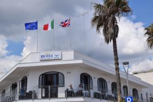 three flags on top of a building with a palm tree at Hotel Profumo Di Mare in Otranto