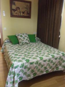a bedroom with a bed with a green and white comforter at Apartamentos Turísticos La Garza in Cáceres