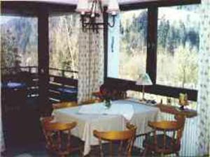 a dining room with a table and chairs and windows at Ferienwohnungen Mahlke in Berchtesgaden