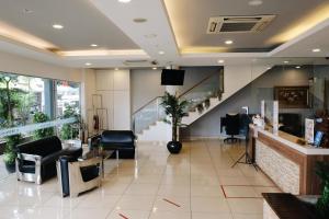 un salón con una sala de espera con sillas y una escalera en De Era Hotel, en Seri Kembangan