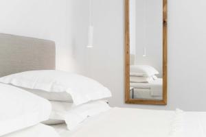 a bedroom with white pillows and a mirror at Armonia Bay Hotel in Kokkari