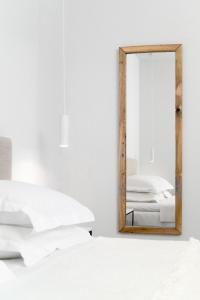 a mirror on a white wall next to a bed at Armonia Bay Hotel in Kokkari