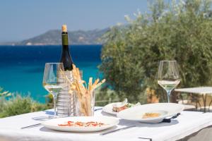 a table with two plates of food and a bottle of wine at Armonia Bay Hotel in Kokkari