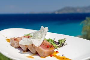 a white plate with food on a table at Armonia Bay Hotel in Kokkari