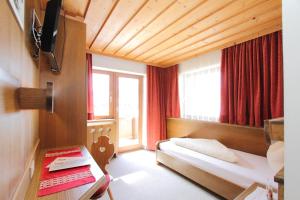 Habitación de hotel con cama y ventana en Pension Mittagskogel, en Sankt Leonhard im Pitztal