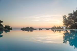 a pool of water with trees in the background at Armonia Bay Hotel in Kokkari