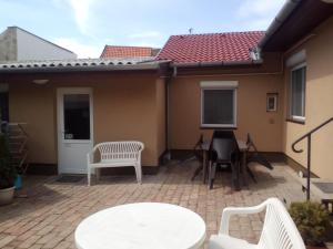 un patio con tavolo e sedie bianchi e una casa di START Apartmanok a Pécs