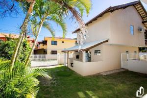 een huis met palmbomen ervoor bij Casa com 03 dormitórios de casal in Bombinhas