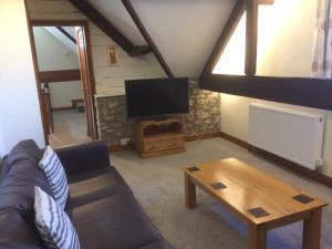 Mill Lodge في ويلْزْ: غرفة معيشة مع أريكة وتلفزيون بشاشة مسطحة