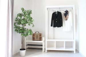 un armario blanco con una chaqueta negra y una planta en Il Melograno en Prato